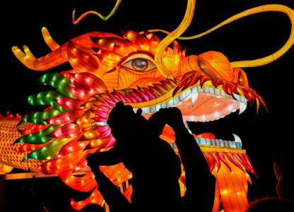 A man and a toddler are silhouetted as they pose for a souvenir photo with a giant dragon lantern decorated near the popular Houhai Lake in Beijing, Thursday, Feb. 8, 2024. Chinese celebrated Lunar New Year on Feb. 10 which marked the Year of the dragon on the Chinese zodiac. (AP Photo/Andy Wong)