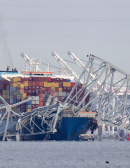A container ship rests against wreckage of the Francis Scott Key Bridge on March 26, 2024, as seen from Pasadena, Md. The ship rammed into the major bridge in Baltimore, causing it to collapse in a matter of seconds and creating a terrifying scene as several vehicles plunged into the chilly river below. (AP Photo/Mark Schiefelbein)