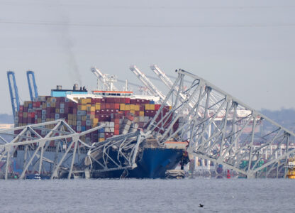 A container ship rests against wreckage of the Francis Scott Key Bridge on March 26, 2024, as seen from Pasadena, Md. The ship rammed into the major bridge in Baltimore, causing it to collapse in a matter of seconds and creating a terrifying scene as several vehicles plunged into the chilly river below. (AP Photo/Mark Schiefelbein)
