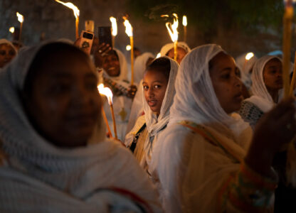 An Ethiopian Orthodox Christian pilgrim looks at the camera as she holds a candle during the procession of the Holy Fire at the Ethiopian monks’ village Deir Al-Sultan, located on the rooftop of the Church of the Holy Sepulchre where many Christians believe Jesus was crucified, buried and rose from the dead, in the Old City of Jerusalem, May 4, 2024. (AP Photo/Leo Correa)