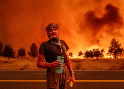 Grant Douglas pauses to drink water while evacuating as the Park Fire jumps Highway 36 near Paynes Creek in Tehama County, Calif., July 26, 2024. (AP Photo/Noah Berger)