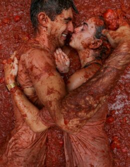 Revelers lie in a pool of squashed tomatoes during the annual “Tomatina” tomato fight fiesta, in the village of Bunol near Valencia, Spain, Aug. 28, 2024. (AP Photo/Alberto Saiz)