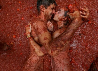 Revelers lie in a pool of squashed tomatoes during the annual “Tomatina” tomato fight fiesta, in the village of Bunol near Valencia, Spain, Aug. 28, 2024. (AP Photo/Alberto Saiz)